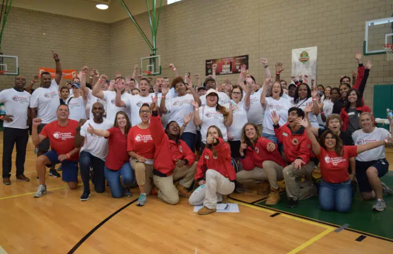 People cheer in red and white shirts in a gymnasium